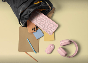 A backpack with a bunch of products spilling out, including a pink keyboard, mouse, and headphones.